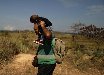 Un migrante con su hijo cruzan a Brasil. Ya son 168.000 los venezolanos que se instalaron en Brasil según la ONU.