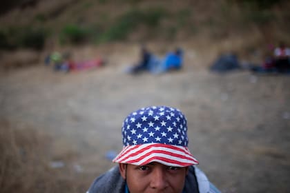 Un migrante hondureño lleva un sombrero con las barras y estrellas de Estados Unidos, y posa para una foto en un bloqueo de carretera tripulado por soldados y policías guatemaltecos, en Vado Hondo