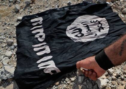 Un miliciano sirio quema una bandera de Estado Islámico en Raqqa, noreste de Siria (Archivo) 