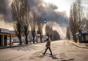 Un militar ucraniano monta guardia cerca de un almacén en llamas alcanzado por un proyectil ruso en los suburbios de Kiev el 24 de marzo de 2022.
