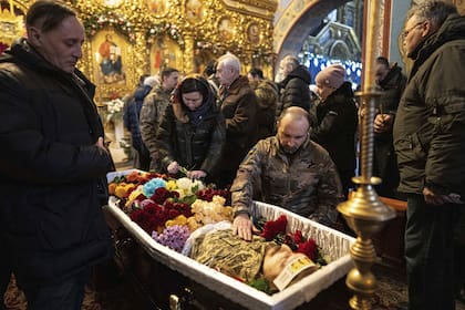 Un militar ucraniano se despide de su camarada Sviatoslav Romanchuk durante una ceremonia fúnebre en el Monasterio de las Cúpulas Doradas de San Miguel en Kiev, Ucrania, el miércoles 3 de enero de 2024.  (AP/Evgeniy Maloletka)
