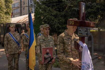 Un militar ucraniano sostiene el retrato de Andrii Veremiienko, quien murió luchando contra las tropas rusas en la región de Donetsk, durante una ceremonia fúnebre en Kiev el 17 de agosto de 2023, en medio de la invasión rusa de Ucrania