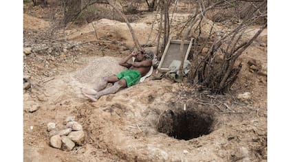 Un minero descansa junto al agujero de la mina