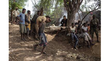 Un minero lleva un saco de tierra para tamizar y filtrar y pasa por un mercado improvisdo