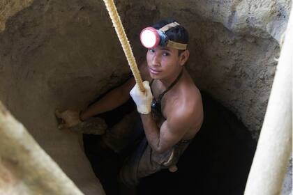 Un minero utiliza una polea rudimentaria para descender a un agujero excavado en una mina de oro en El Callao, sur de Venezuela