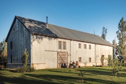 Un moderno galpón que cumple muchísimos usos rodeado de un monte frutal.