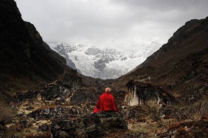 Un monje meditando frente al impresionante glaciar Jomo Lhari (7326m, la montaña más alta de Bután) que desaparece en las nubes