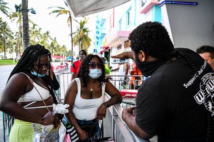 Un mozo toma la temperatura a dos clientas antes de entrar a un restaurante en la calle Ocean Drive, en South Beach, Florida