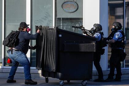 Un manifestantes se refugia tras un contenedor de basura