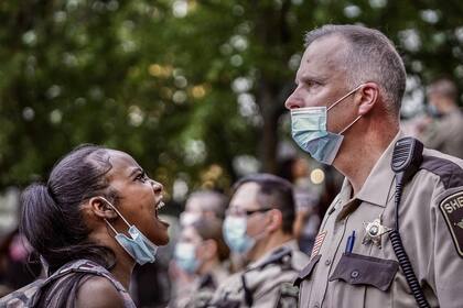 Una manifestante le grita a un policía que parece ignorala.