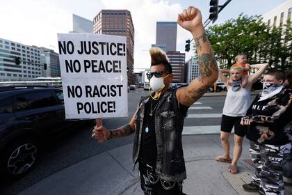 Un hombre sostiene un cartel en la ciudad de Denver; se realizaron protestas en varias ciudades de EE.UU.