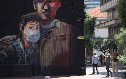 Un mural muestra a una joven con un barbijo en Bogotá, el lunes 13 de abril de 2020. Hay coincidencia en que el gobierno de Duque tuvo una buena política de vacunación nacional, pero una mala respuesta de asistencia a los sectores más afectados
