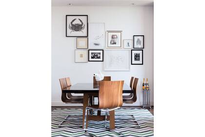 Un muro con una linda composición de cuadros, fotos y láminas sirve de marco y delimita el área del comedor