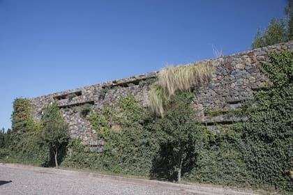 Un muro de hormigón y piedras hace de soporte de maceteros embutidos con riego por goteo.