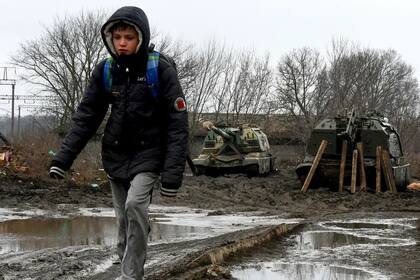 Un niño camina con dos tanques a su espalda