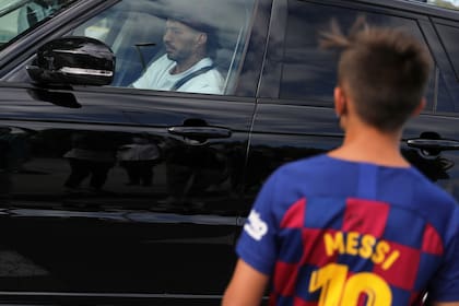 Un niño con la camiseta de Messi ve la llegada de Luis Suárez a las pruebas médicas en la Ciudad Deportiva Joan Gamper