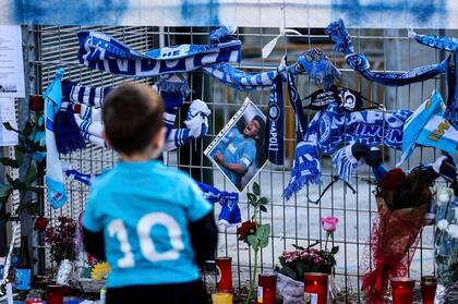 Un niño con la camiseta número 10 del Napoli se detiene junto a los recuerdos de Diego Armando Maradona en una de las valla del estadio San Paolo en Nápoles