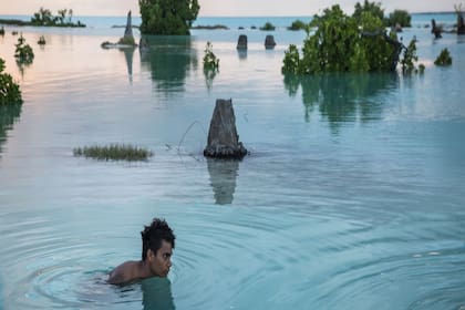 Un niño de 16 años nada en la zona inundada de la aldea de Aberao en Kiribati. La isla del Pacífico es uno de los países más afectados por el aumento del nivel del mar.