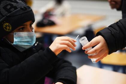 Un niño de una clase escolar da su muestra para la llamada 'prueba de piruleta', que es una prueba de PCR en grupo para el coronavirus, en la escuela primaria de Petri en Dortmund, en el oeste de Alemania, el 23 de noviembre de 2021, en medio del nuevo coronavirus / Pandemia de COVID-19