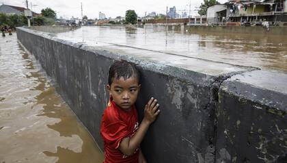 Un niño indonesio junto a un muro en una carretera inundada en Yakarta, Indonesia, el 2 de enero de 2020. EPA/MAST IRHAM