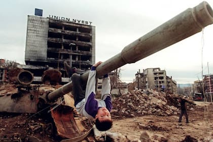 Un niño juega en un tanque entre las ruinas de Sarajevo