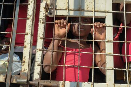 Un niño junto con personas detenidas para ser deportadas hacia Haití en un camión policial (Archivo AP/Ricardo Hernandez)
