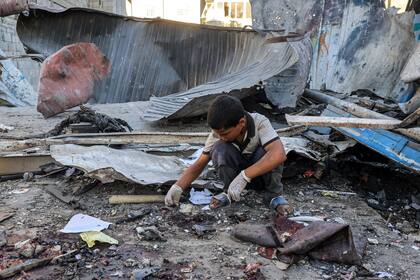 Un niño mira los escombros de un edificio derrumbado tras el bombardeo israelí en la escuela Jauni dirigida por la Agencia de Obras Públicas y Socorro de las Naciones Unidas para los Refugiados de Palestina (OOPS) en Nuseirat, en el centro de la Franja de Gaza