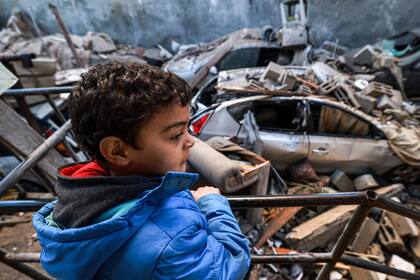 Un niño observa mientras está parado junto a escombros y un vehículo destruido después del bombardeo israelí en Rafah, en el sur de la Franja de Gaza, el 7 de febrero de 2024
