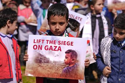 Un niño palestino que vive en Líbano sostiene un cartel durante una protesta para exigir un alto el fuego y apoyar a los palestinos en la Franja de Gaza, frente a la sede de la Comisión Económica y Social de las Naciones Unidas para Asia Occidental (CESPAO) en Beirut, Líbano, el jueves 29 de febrero de 2024. 