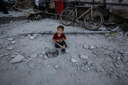Un niño palestino se sienta entre los daños causados ​​después de un ataque aéreo israelí contra una escuela