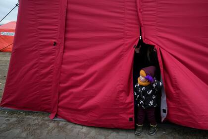 Un niño pequeño mira desde la entrada a una carpa en un centro de ayuda humanitaria para personas desplazadas que huyen de Ucrania, en Przemysl, Polonia