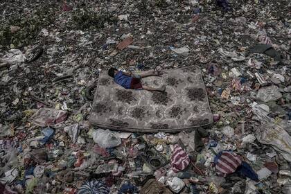 Un niño que recolecta material reciclable de la basura, descansa en un colchón que flota sobre el Río Pasig, en Manila, Filipinas. Nominada en la categoría Medio Ambiente