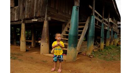 Un niño se encuentra en el frente de una casa construida sobre las bombas