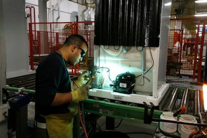 Un obrero trabajando en el motor de una heladera
