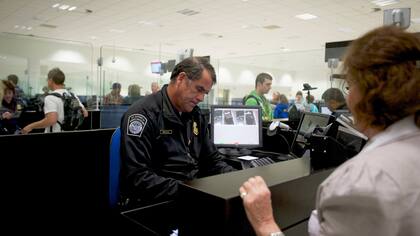 Un oficial de Aduanas y Protección Fronteriza de Irlanda, inspeccióna los documentos de viaje del pasajero como parte de un programa de autorización previa