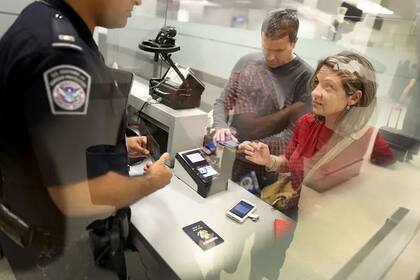 Un oficial de la CBP supervisa el ingreso de pasajeros en un aeropuerto de Estados Unidos, en el inicio de la temporada de viajes de verano