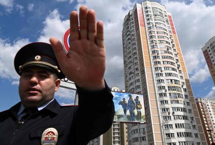 Un oficial de policía asegura un área fuera de un edificio de apartamentos de varios pisos dañado después de un ataque con drones reportado en Moscú el 30 de mayo de 2023.
