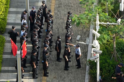 Un oficial de policía chino da instrucciones a los guardias de seguridad de servicio alrededor de la sede de Evergrande en Shenzhen, en el sur de China
