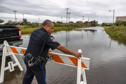 Un oficial de policía de Charleston erige una barrera donde la marea cubrió Hagood Avenue, el jueves 29 de septiembre de 2022 (The Post and Courier/Andrew J. Whitaker)