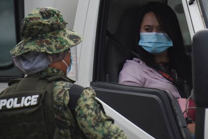 Un oficial de policía habla controla la identidad de una mujer durante una nueva ronda de medidas de bloqueo por el brote de coronavirus, en Manila el 4 de agosto de 2020