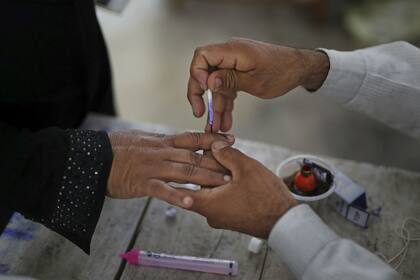 Un oficial de votación pone tinta indeleble en el dedo de un votante en una mesa electoral en la aldea de Shahpur, cerca de Muzaffarnagar, India