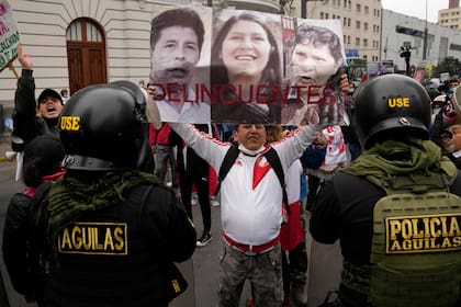 Un opositor al gobierno del presidente Pedro Castillo sostiene fotografías de Castillo, su cuñada Yenifer Paredes y su esposa Lilia Paredes con la leyenda "Delincuentes", a las afueras de una corte durante una protesta fuera de un tribunal en contra de Yenifer Paredes, el domingo 28 de agosto de 2020, en Lima