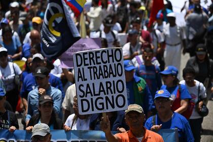 Un opositor al gobierno venezolano sostiene un cartel en el que se lee "Derecho al trabajo. Salario digno" mientras participa en una marcha para conmemorar el Primero de Mayo (Día del Trabajo) en Caracas el 1 de mayo de 2023.