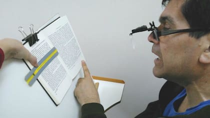 Un paciente con baja visión utilizando ayuda óptica y una guía de lectura