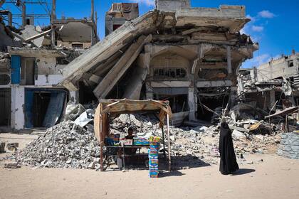 Un palestino desplazado muestra alimentos para la venta frente a edificios destruidos en Khan Yunis, en el sur de la Franja de Gaza, el 24 de mayo de 2024, en medio del conflicto en curso entre Israel y el movimiento Hamas.