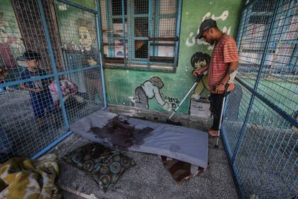 Un palestino inspecciona un colchón ensangrentado después del ataque israelí a una escuela de la ONU en la Franja de Gaza