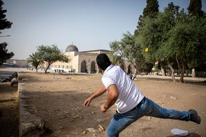 Un palestino lanza una piedra contra la policía israelí que busca dispersar manifestantes palestinos junto a la Mezquita de Al-Aqsa, Jerusalén, el 10 de mayo de 2021