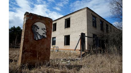 Un panel con un retrato de Lenin y un edificio abandonado se ven en la zona de exclusión de 30 km alrededor del reactor nuclear de Chernobyl en la aldea abandonada de Orevichi, Bielorrusia