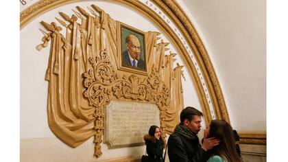 Un par de besos delante de un mosaico que representa el fundador del estado soviético Vladimir Lenin en la estación de metro Kievskaya en Moscú, Rusia