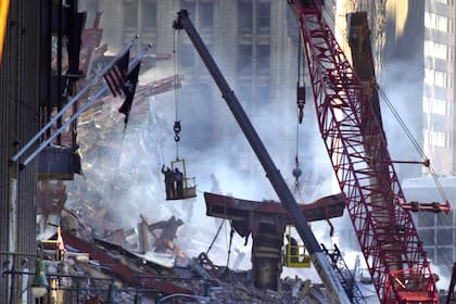 Un par de soldadores son sacados de los escombros con una grúa después de cortar una sección de metal en el sitio del desastre del World Trade Center, el sábado 15 de septiembre de 2001
